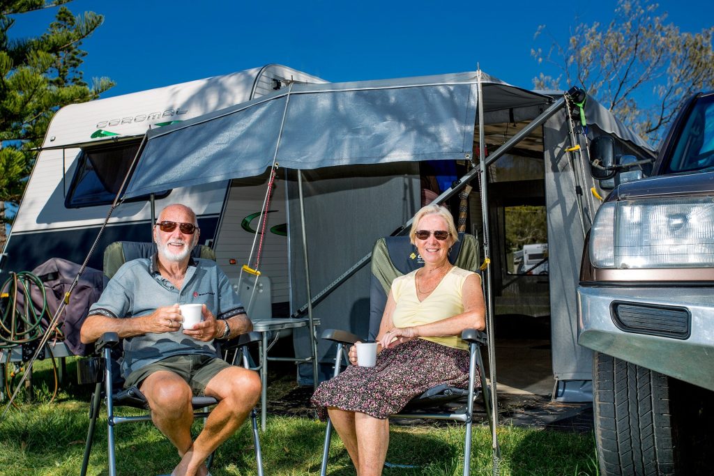 Couple sitting in front of caravan on holiday at Reflections Holiday Parks Corindi Beach