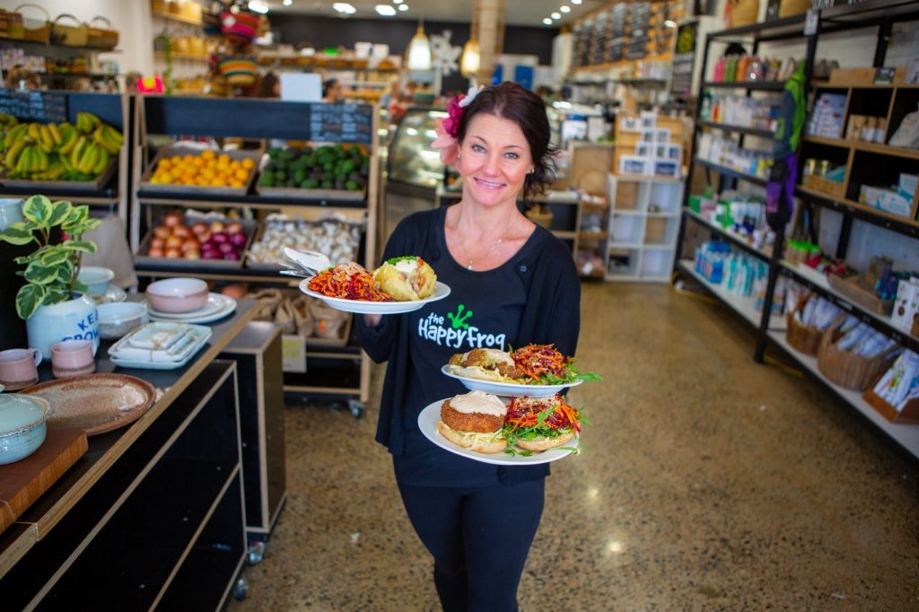 Waitress carrying healthy food with pottery, fruit and vegetables and groceries behind her