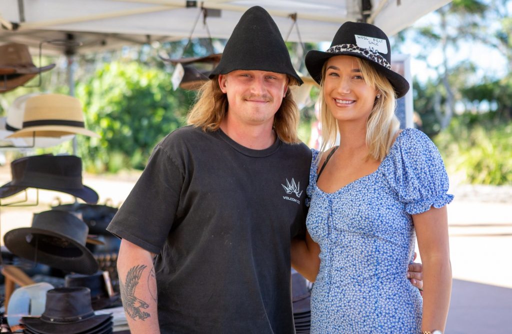 Couple standing in front of hat stall at the markets