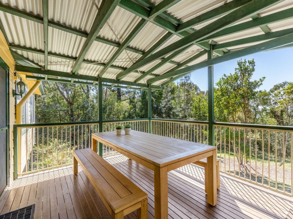 The verandah with outdoor table and benches at Tuckers Rocks Cottage in Bongil Bongil National Park.
