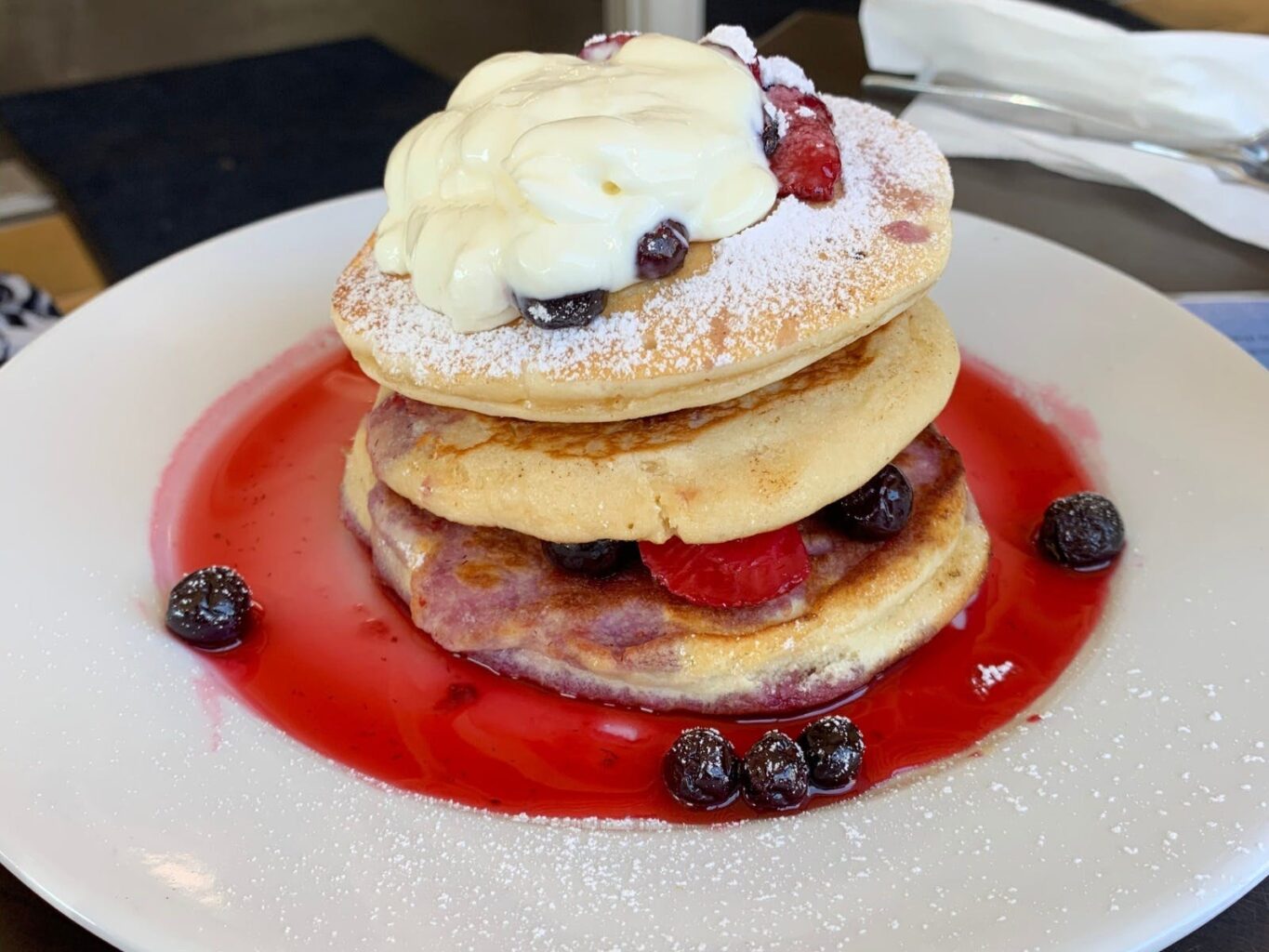 Pancake stack with strawberries & blueberries & topped with yoghurt