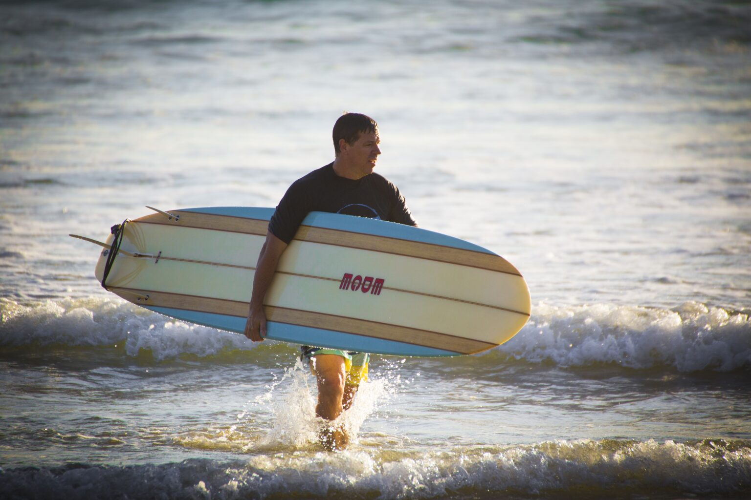 Surfer carrying a longboard surfboard