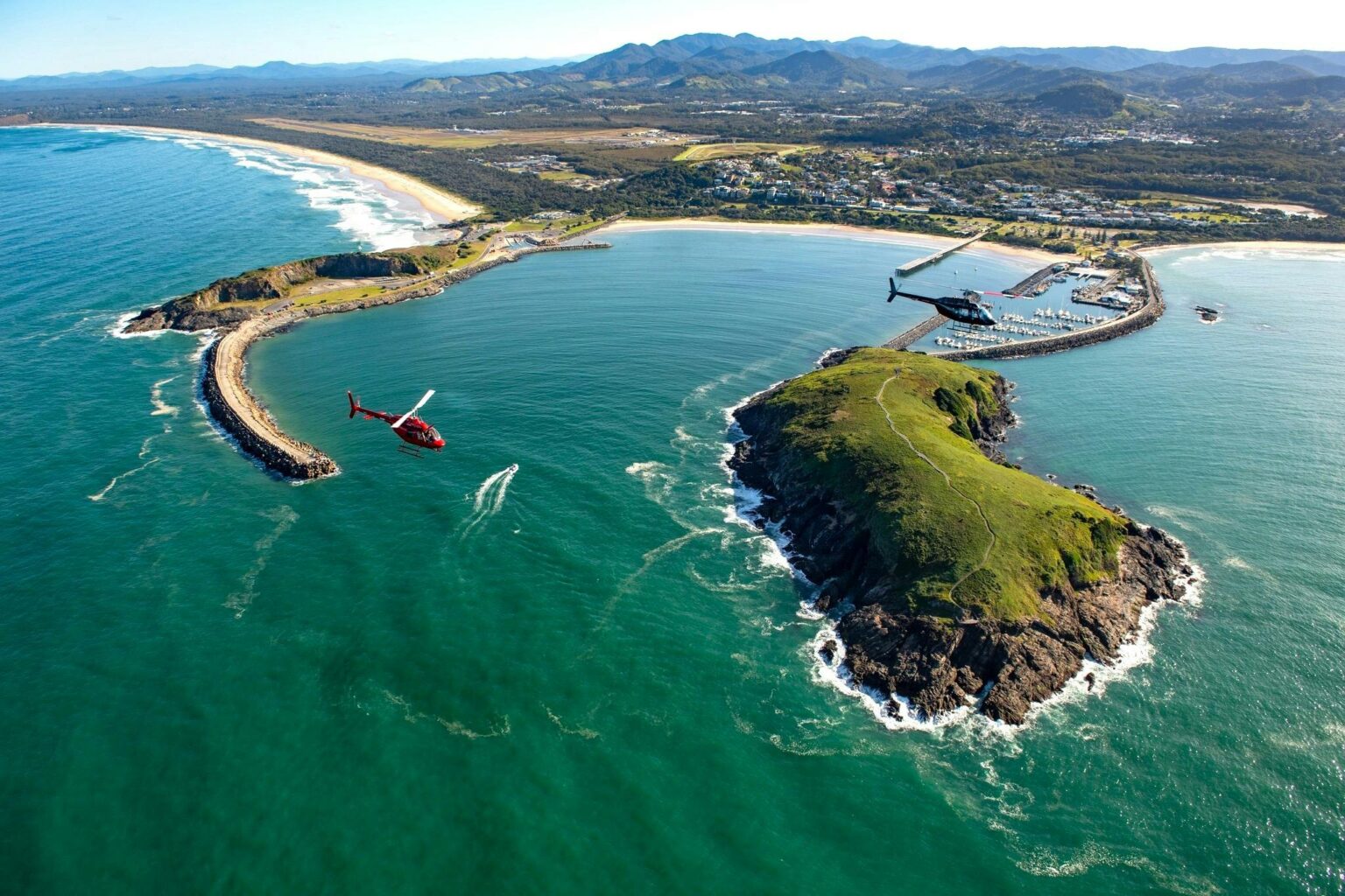 Coffs Harbour with the harbour,  Muttonbird Island and two scenic helicopters in view