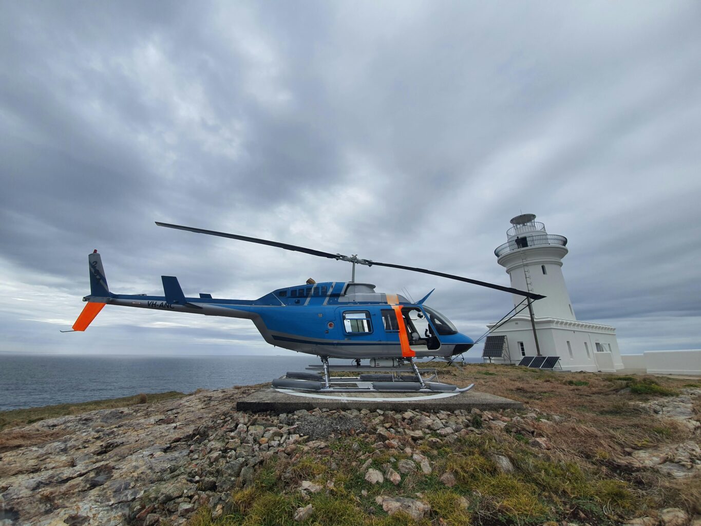 South Solitary Island Lighthouse with Helicopter, green grass and light clouds